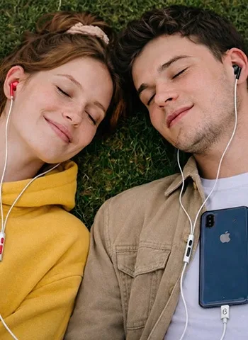 Couple relaxing on grass while using loveBuds