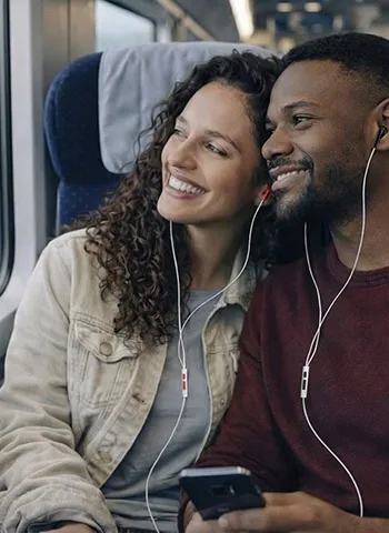 Couple sharing loveBuds on a train